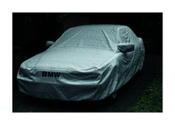 BMW car covered in a white sheet standing on a dark driveway.