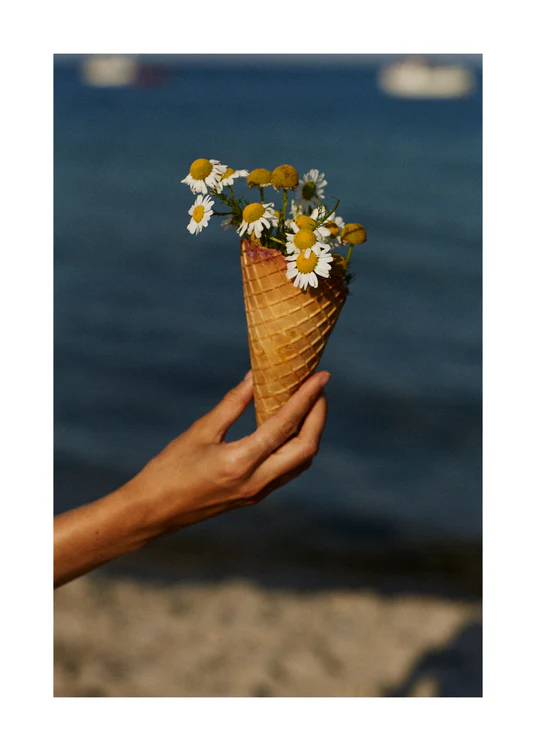 Ice cream cone full of white flowers in front of a blue sea.