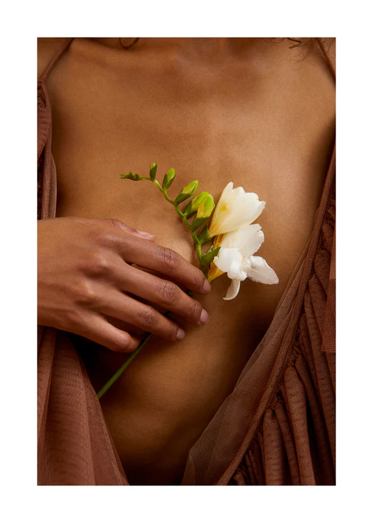 A woman wearing a low-cut dress covering her chest with a white flower.