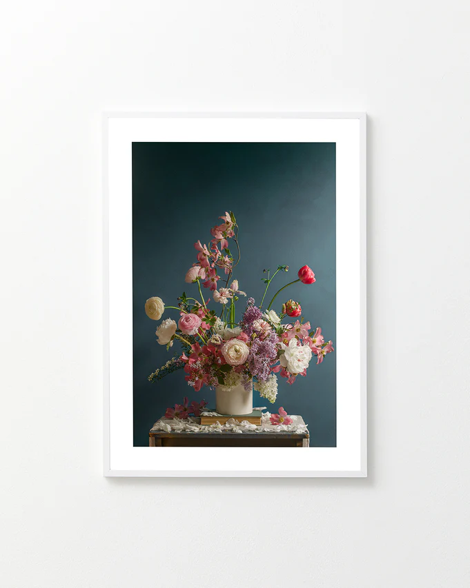 The Spring Ballet Poster features a framed photograph of a floral arrangement with pink, white, and purple flowers against a dark teal background, displayed on a wooden table.
