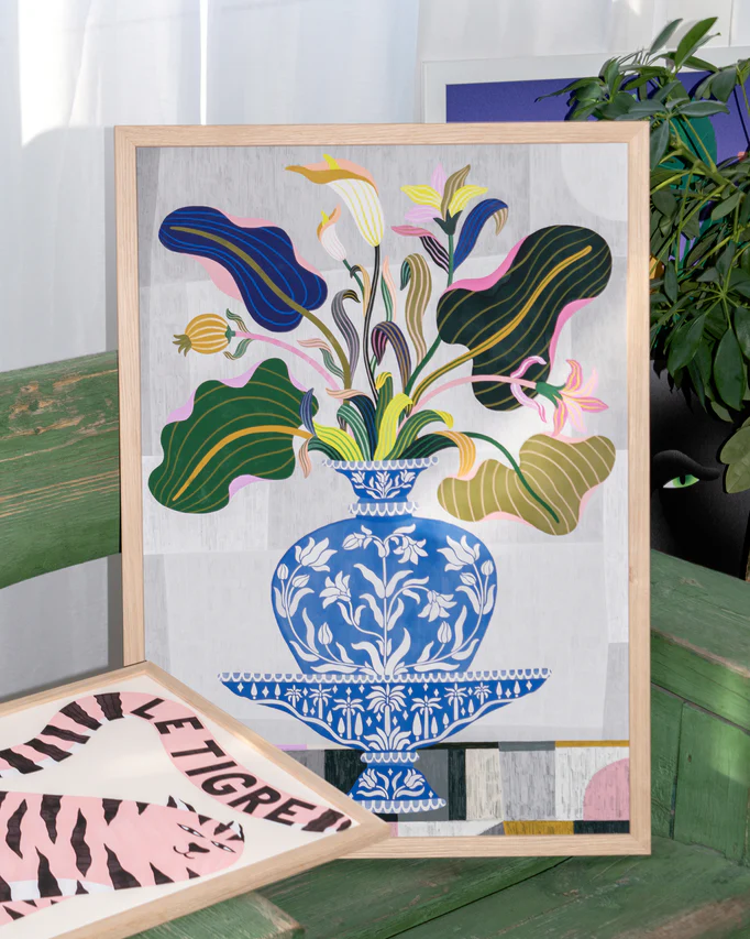 The Vase Poster features a framed painting of a blue vase with colorful leaves and flowers on a green bench, capturing the charm of traditional Persian and Indian art. Beside it is an abstract shapes artwork, with a background plant adding an organic touch.