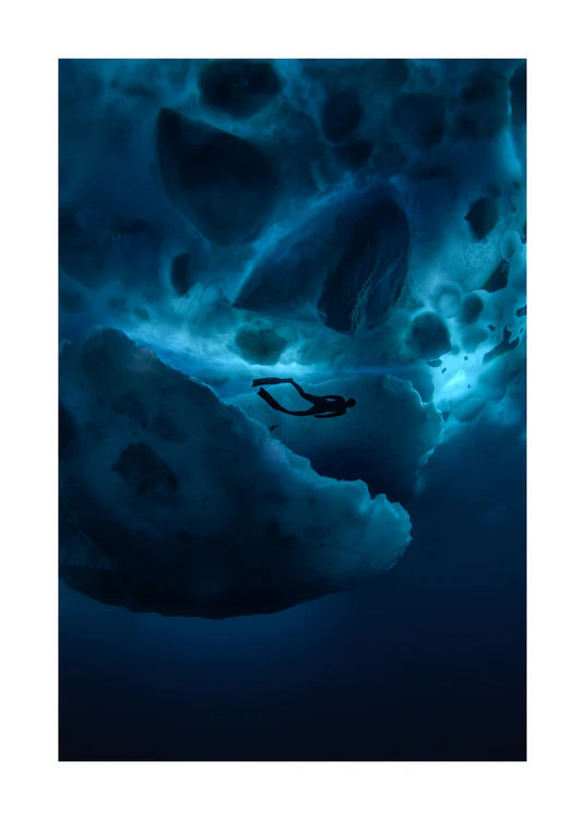 Diver swimming underneath ice bergs.