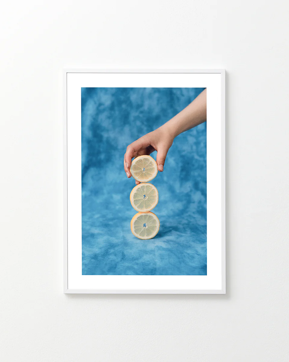 Three slices of freshly cut lemon on top of each other on a blue background.