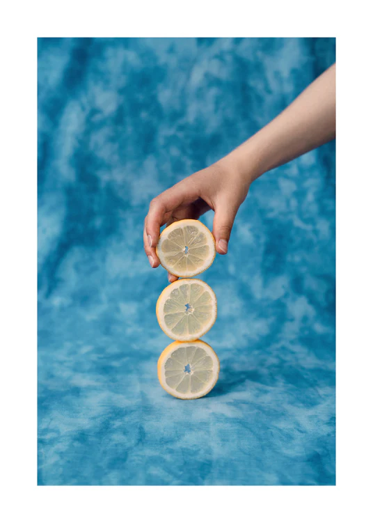 Three slices of freshly cut lemon on top of each other on a blue background.