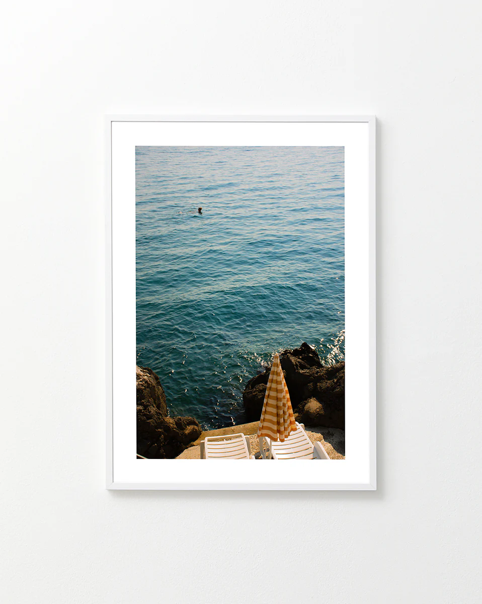 Tanning beds and a beach umbrella on the shore of the blue, Croatian sea.