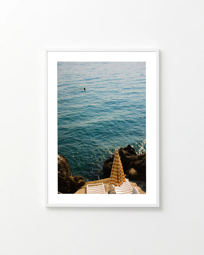 Tanning beds and a beach umbrella on the shore of the blue, Croatian sea.