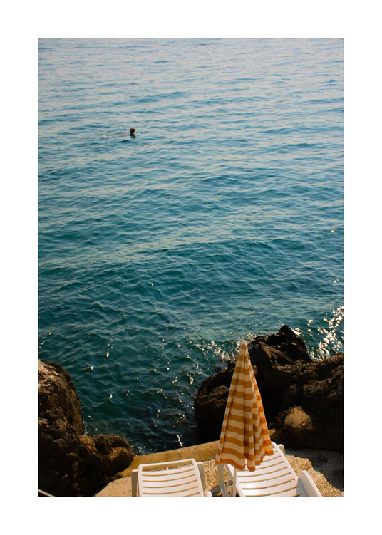 Tanning beds and a beach umbrella on the shore of the blue, Croatian sea.
