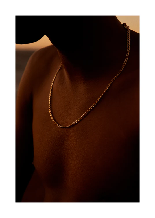 Bare chested man covered in goose bumps and wearing a gold chain necklace.