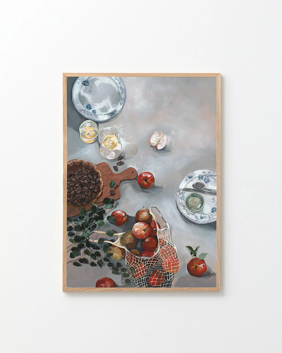 The How Do You Like These Apples Poster showcases a still life scene with red apples, a basket, plates, a cutting board, herbs, a cracked egg, and nuts on a gray tabletop for warm decor and rustic coziness.