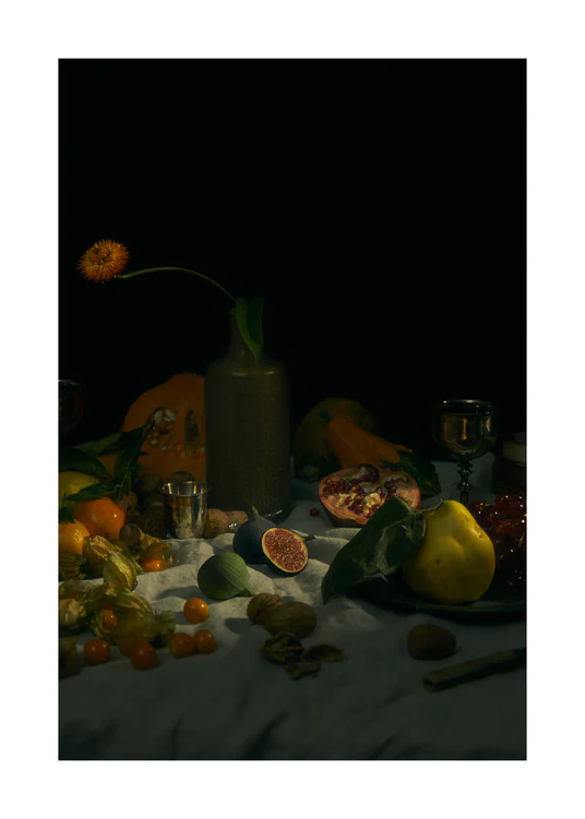 Still life photograph of fruits and flowers on a white canvas.