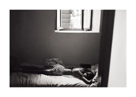 Girl with checkered hotpants lying in bed underneath an open window.