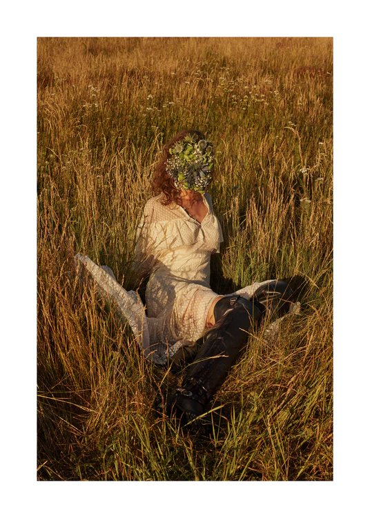 Woman portrayed on a summer meadow with a face mask made of flowers.