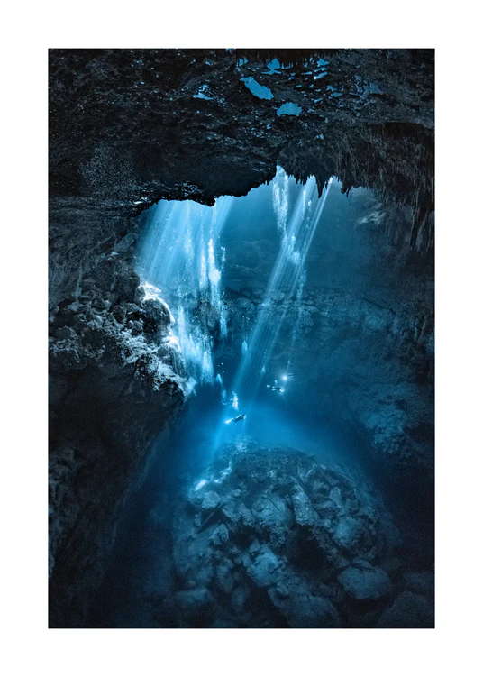 Divers exploring a deep blue water cave.