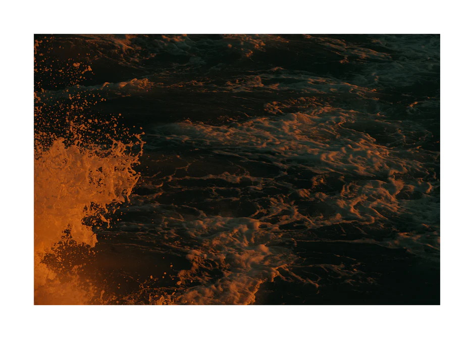 Rushing sea with foam colored crimson by the setting sun.