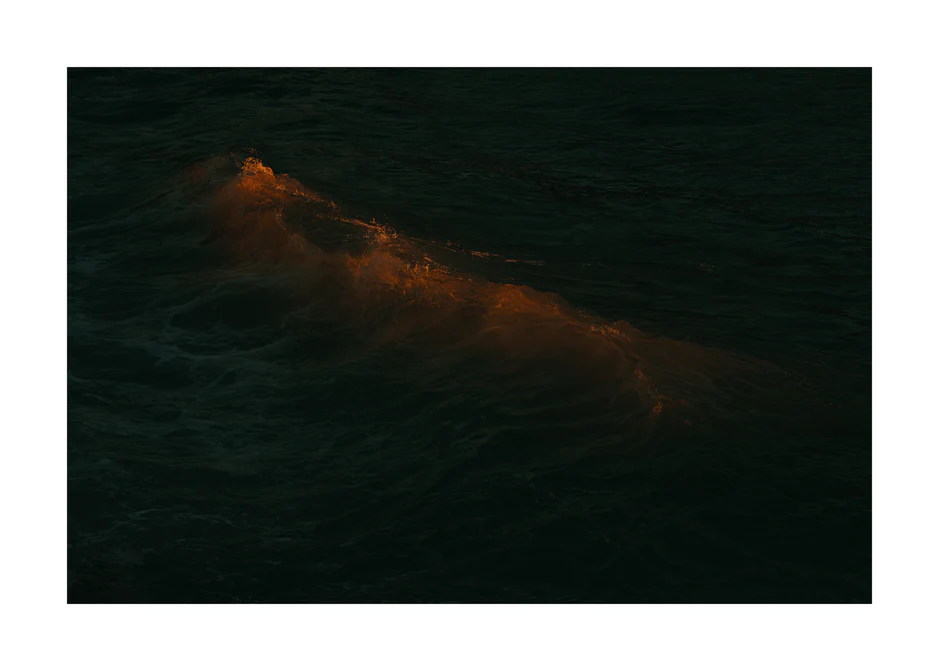 Waves colored orange from the setting sun in the ocean.