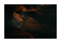 Waves crashing into the cliffs at shore during sunset.