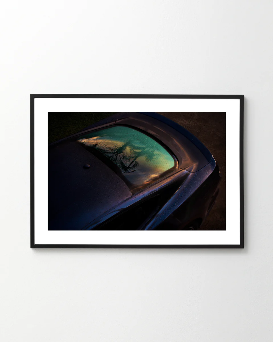 The Gas Up Poster captures a sleek car with dew on the windshield under a vibrant sky, embodying pedal to the metal. Displayed on a plain white wall and viewed from an elevated angle, it highlights dynamic presence.