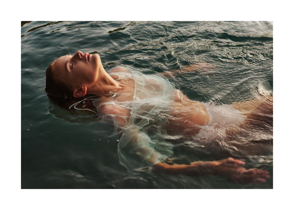 Woman dressed in white floating at the surface of the ocean.