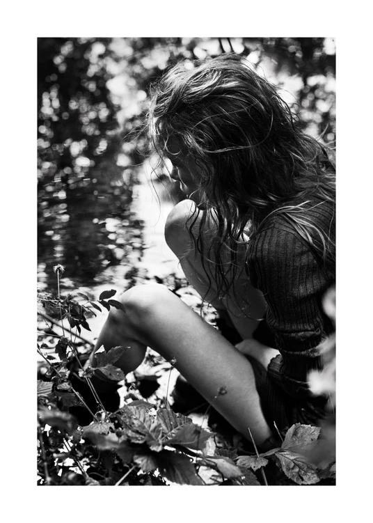Woman captured from above sitting in the forest next to a pond.