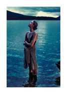 Woman in rubber boots standing in a blue lake and looking at the sky.