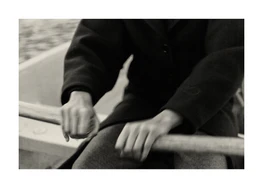 Hands holding the oars and rowing a boat on a black lake.