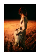 Woman dressed in white standing on an orange field in the night. 